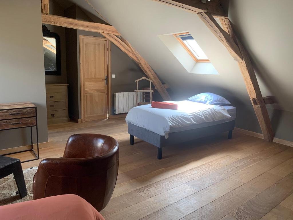 a bedroom with a bed and a chair in a attic at Maison déco avec jardin Tours Châteaux de la Loire in Charentilly
