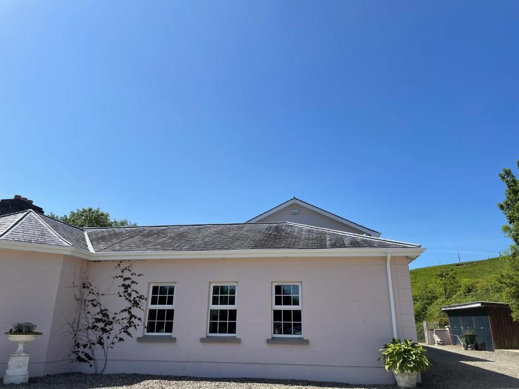 a white house with a hill in the background at The Cottage at Riverbank in Ballinamallard