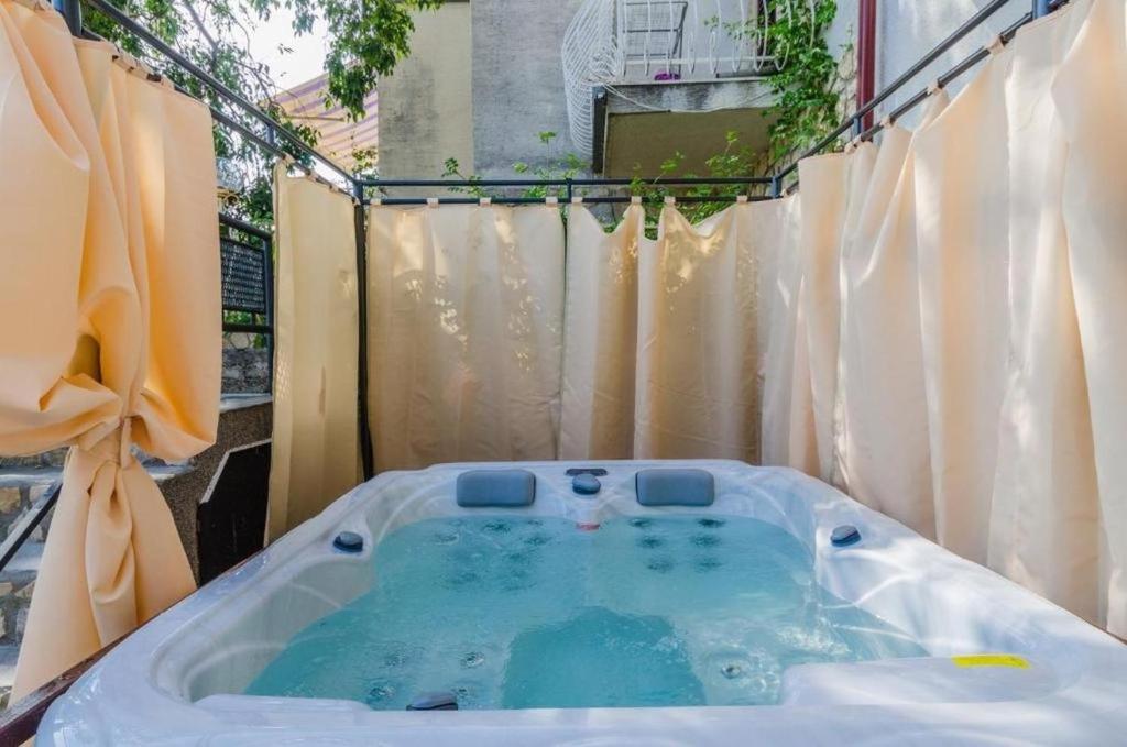 a jacuzzi tub in a yard with curtains at Apartman Draga in Dramalj