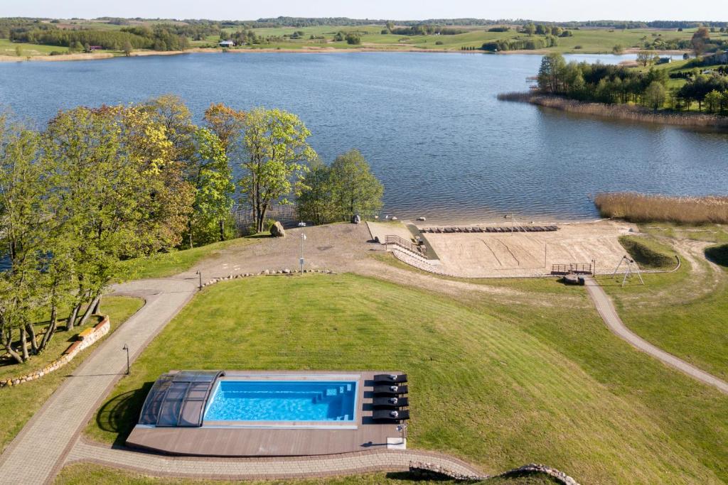 an aerial view of a swimming pool in a field next to a lake at Reketijos Dvaras in Reketija