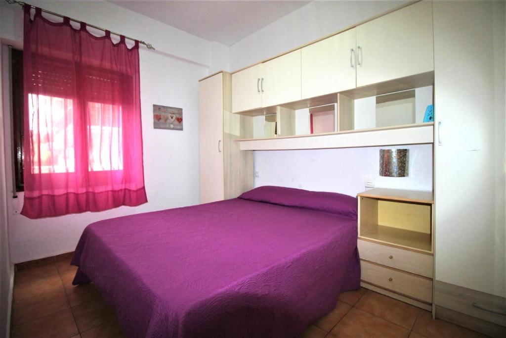 um quarto com uma cama roxa e um armário em Precioso apartamento con piscina WiFi em La Pobla de Farnals
