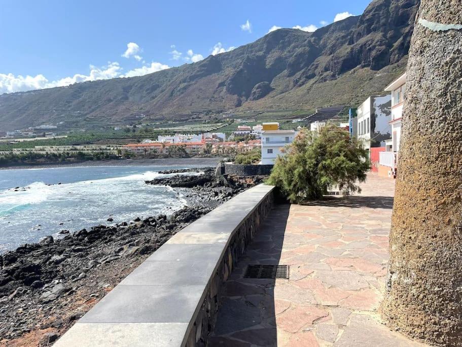 a walkway next to the ocean with mountains in the background at Casa Vacacional Nona in Caleta de Interián