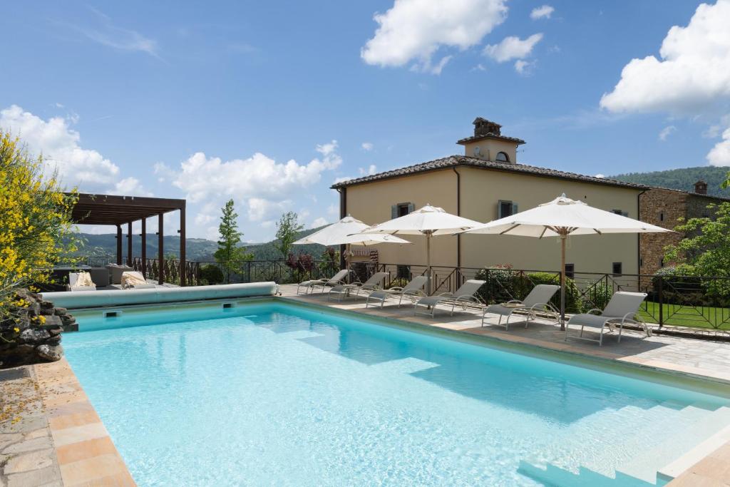 una piscina con sillas y sombrillas frente a una casa en Villa Castelluccio, 