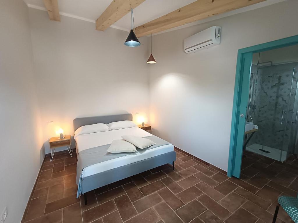 Habitación blanca con cama y baño. en Agriturismo Al posto giusto en Piombino