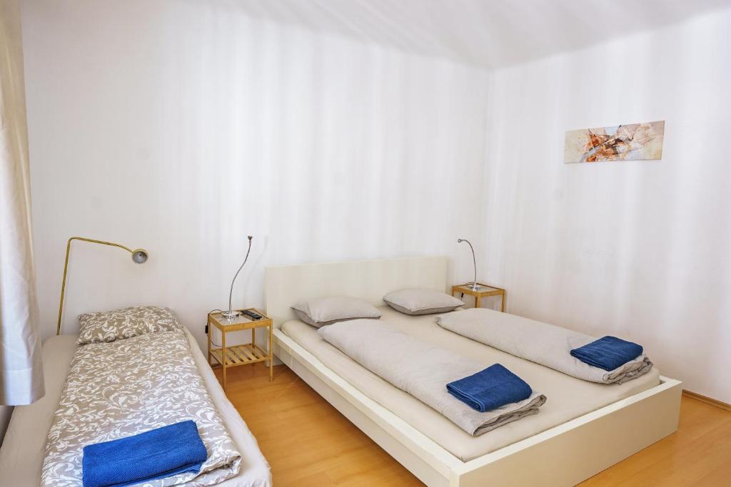 2 bedden in een witte kamer met blauwe kussens bij Vienna Living Apartments - Mühlfeldgasse in Wenen