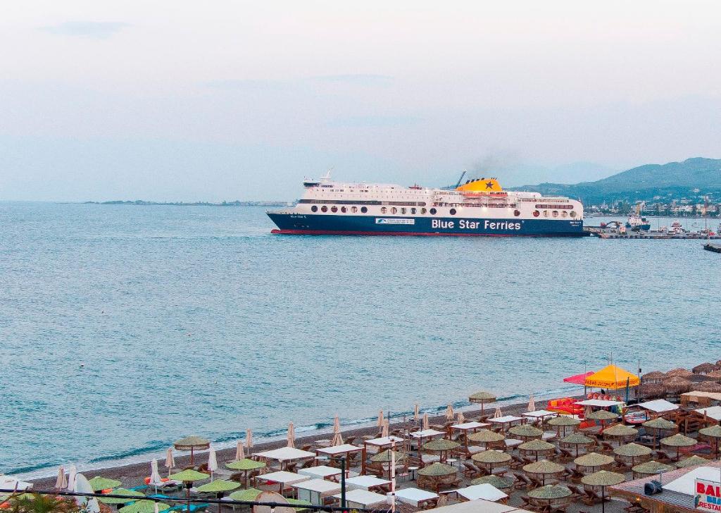 a large ship in the water with umbrellas and a beach at SeaSTAR Beach Apartments in Kos