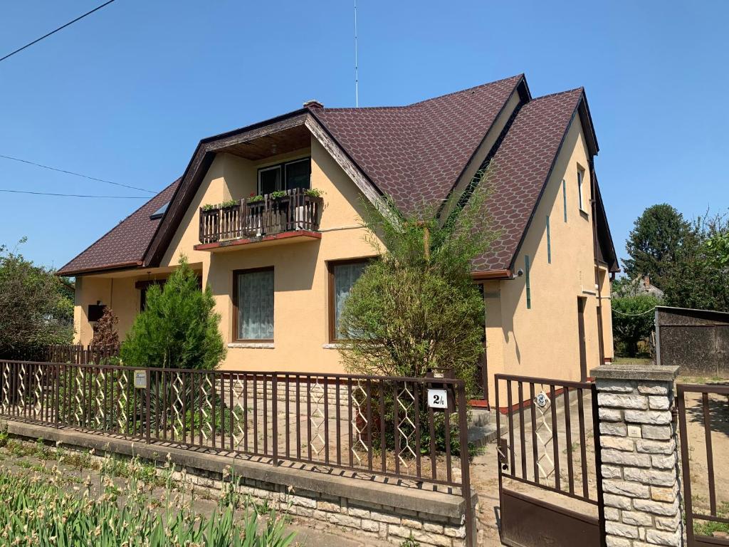 een geel huis met een zwart dak en een hek bij La Casa del Lago in Siófok