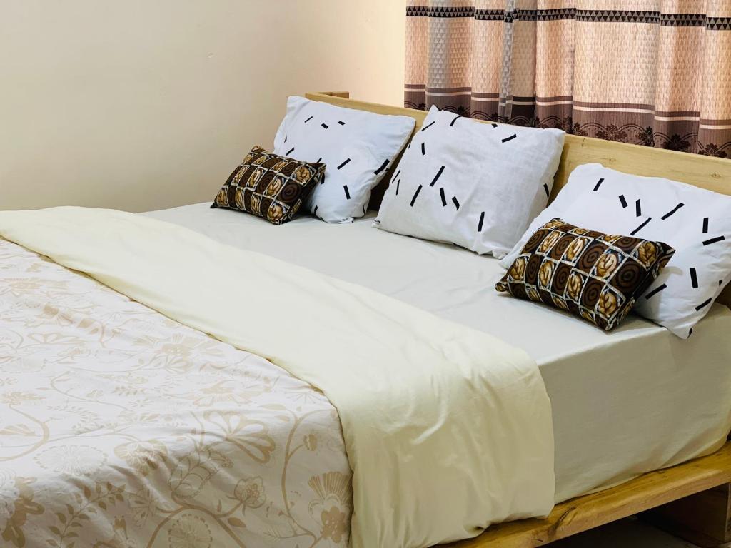 Bett mit weißer Bettwäsche und Kissen in der Unterkunft Virunga Homes in Ruhengeri