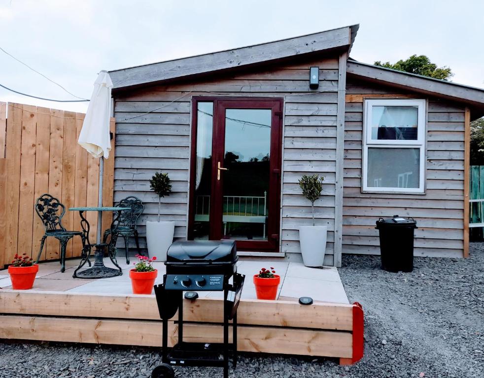 a tiny house with a patio and a grill at The Hut B & B in Mochdre