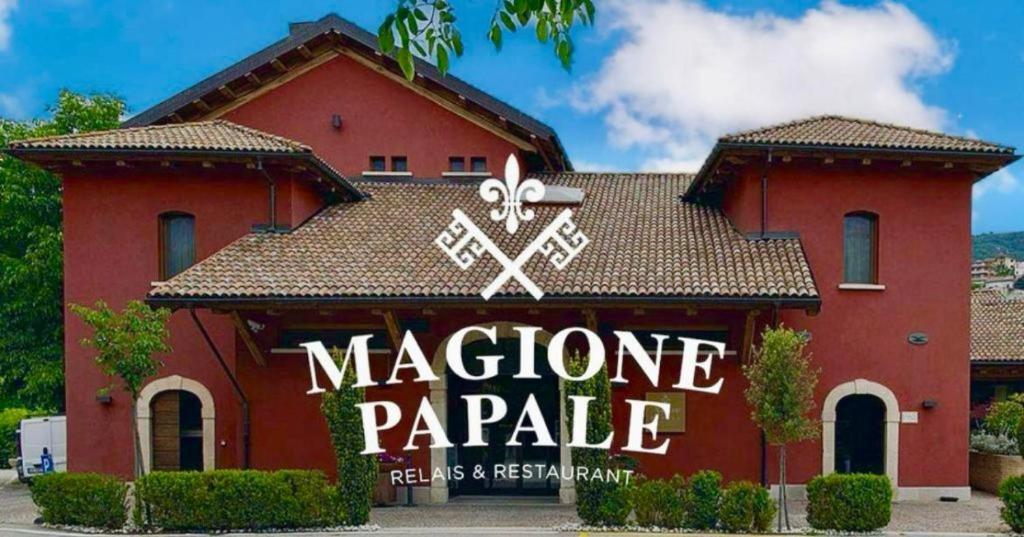 un edificio rojo con un cartel delante en Magione Papale Relais, en LʼAquila