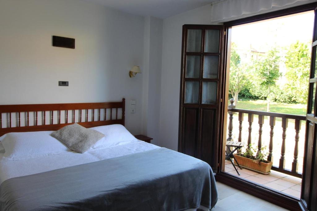 een slaapkamer met een bed en een groot raam bij Hotel Salldemar in Santillana del Mar