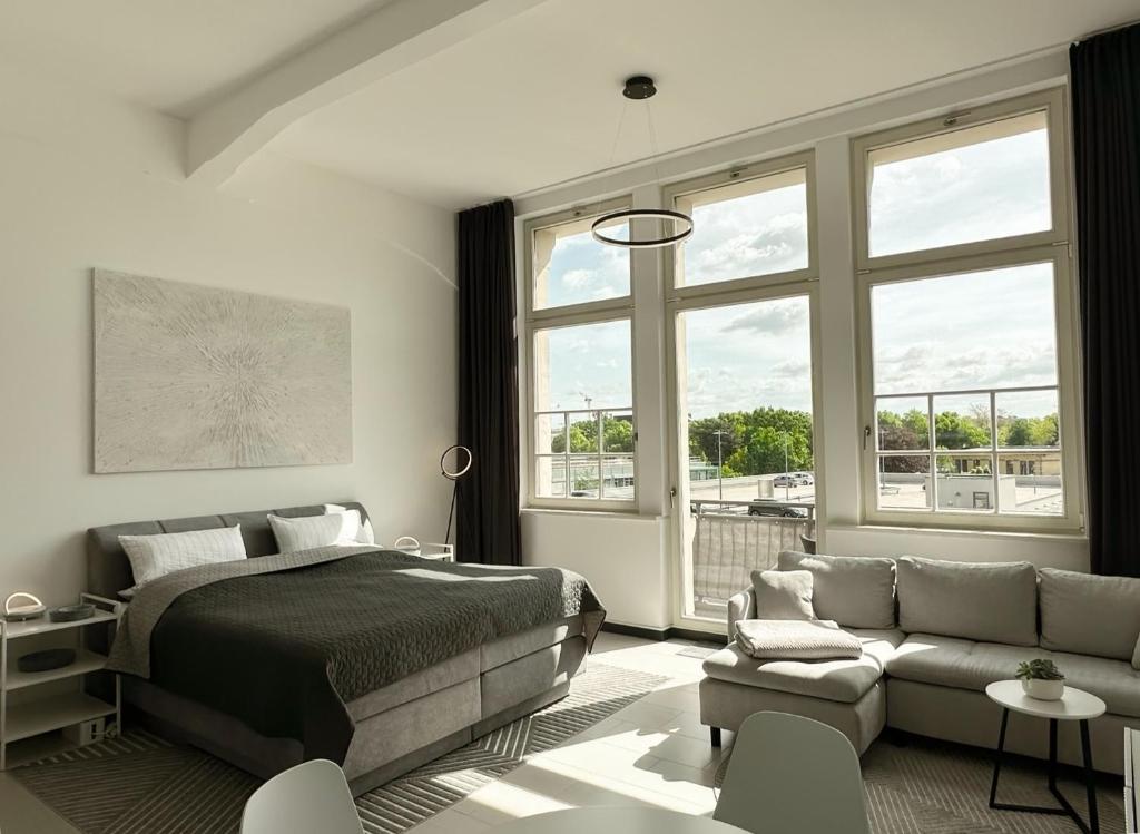 a bedroom with a bed and a couch and windows at MEOS 1 -Zentrum-Balkon-Parkplatz-Gym-Uniklinik in Leipzig
