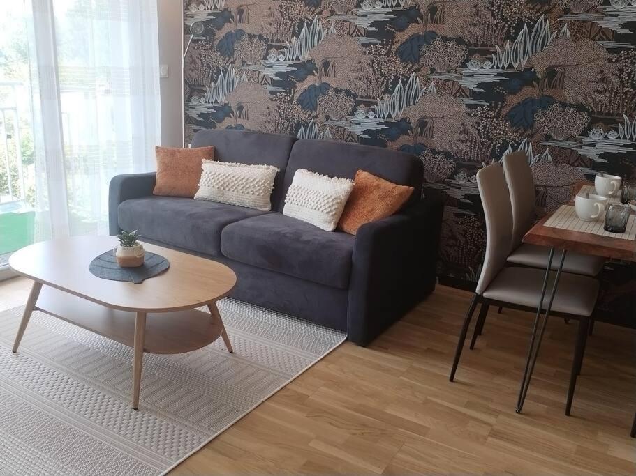 a living room with a blue couch and a table at Appartement neuf classé, balcon et petite vue mer in Pléneuf-Val-André