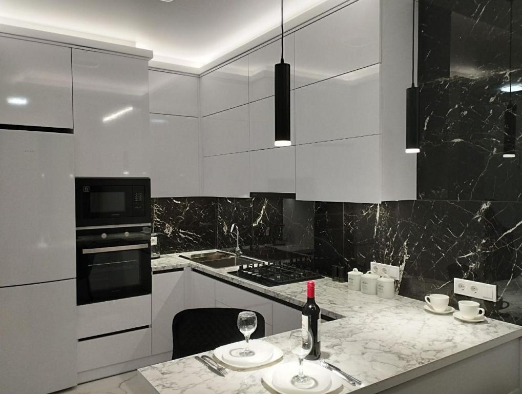 a kitchen with white cabinets and a counter with wine glasses at Елітна квартира-студія . in Ternopil
