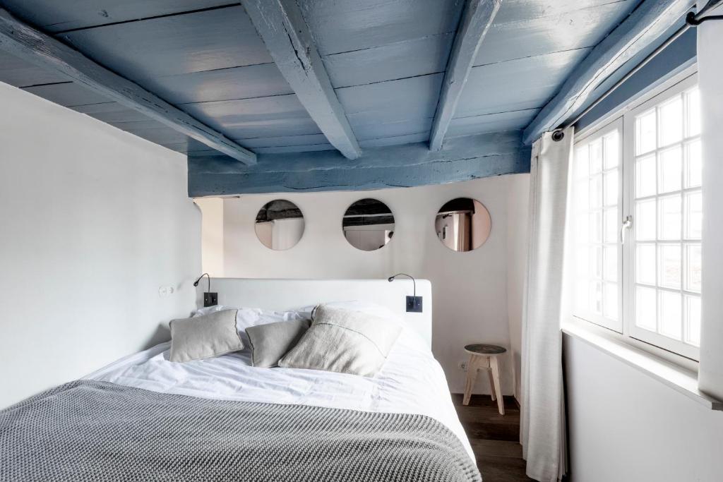 1 dormitorio con cama blanca y techos azules en Het Kostershuisje, en Nuenen