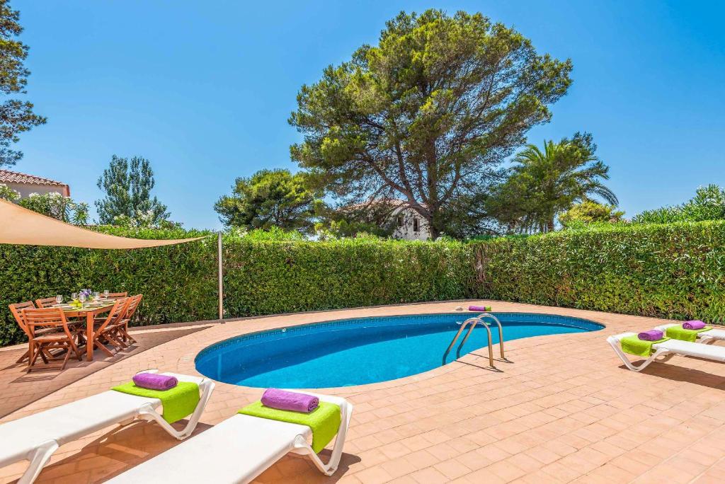 a swimming pool with a table and chairs next to a hedge at Villa Ginevra in Son Bou
