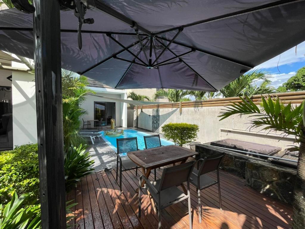patio ze stołem, krzesłami i parasolem w obiekcie Coconut Groove w mieście Grand Baie
