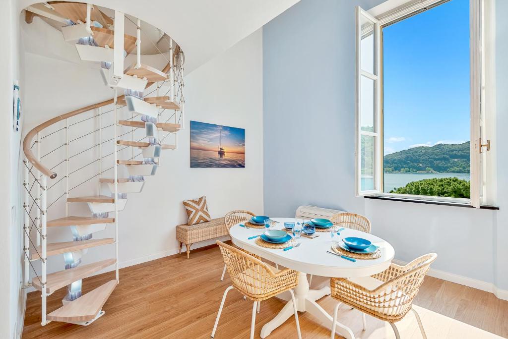 ein weißes Esszimmer mit einer Wendeltreppe sowie einem Tisch und Stühlen in der Unterkunft L'incanto di Venere in Porto Venere