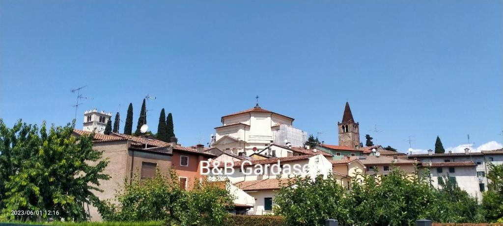 a group of buildings with trees in the foreground at B&B Gardasee in Castelnuovo del Garda