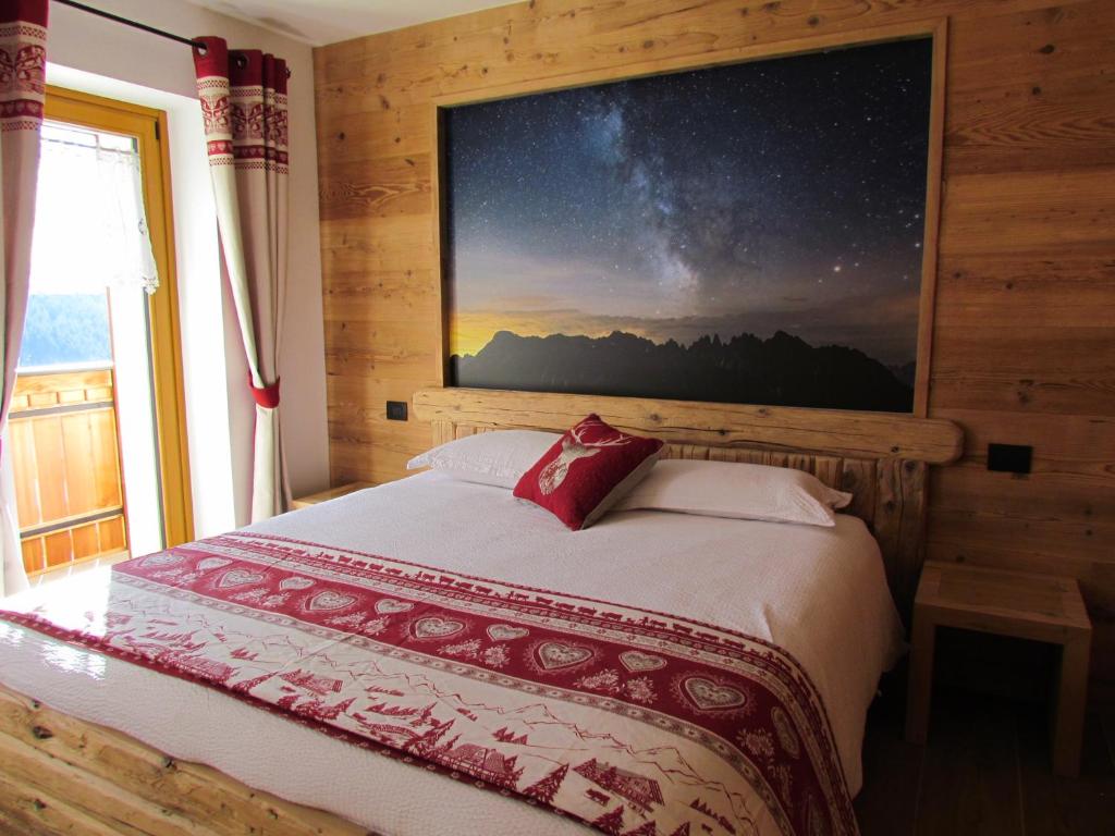 Cuore delle Dolomiti Alloggi Vacanze في سان بيترو دي كادوري: غرفة نوم بسرير مع لوحة على الحائط