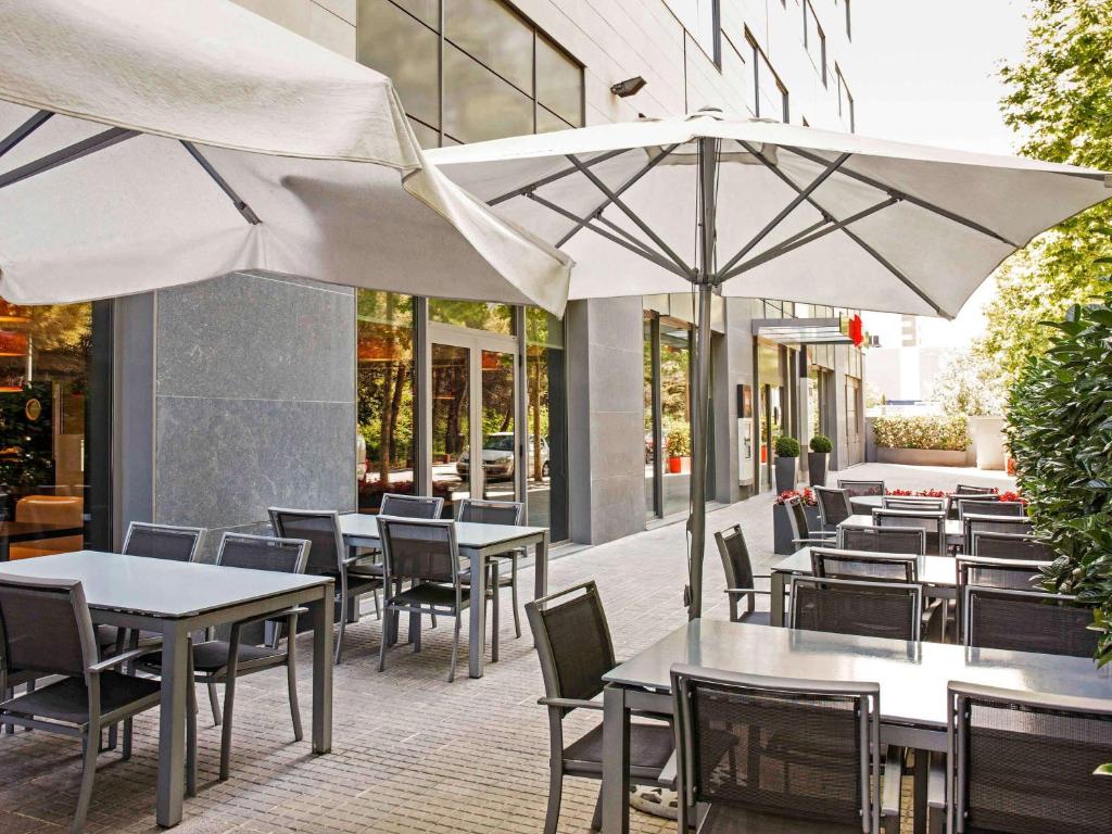 an outdoor restaurant with tables and chairs and umbrellas at Ibis Barcelona Mollet in Mollet del Vallès