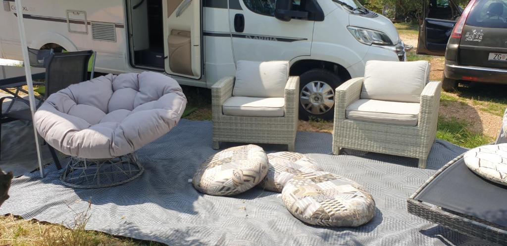 a group of chairs and ottomans in front of an rv at Camper Relax in Murter Slanica beach - with clima in Tisno
