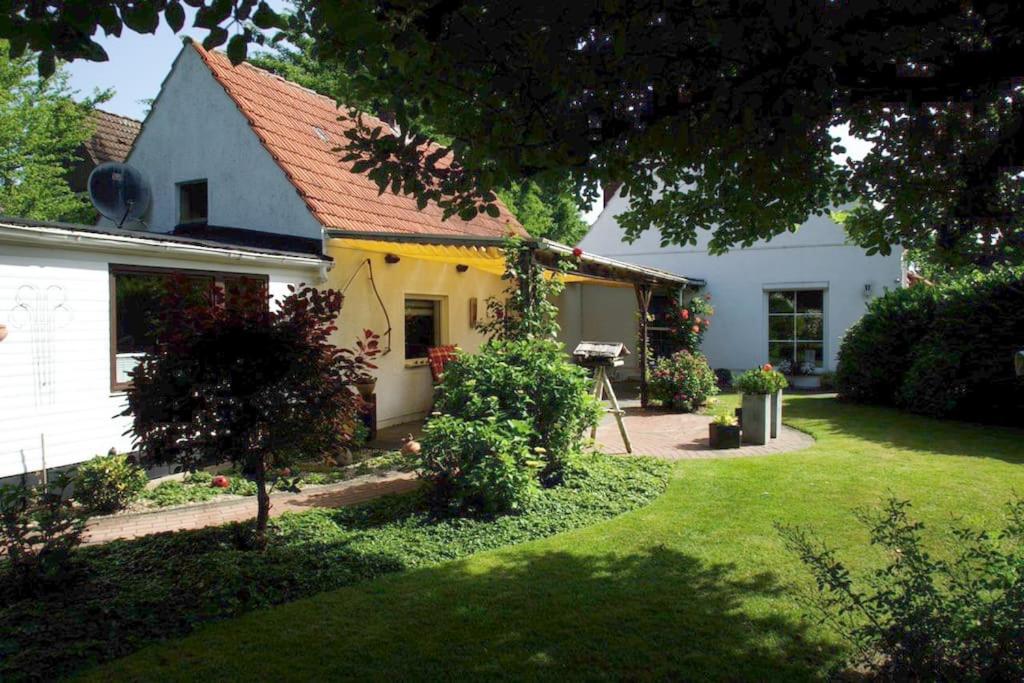 ein weißes Haus mit einem Garten und einem Garten mit Gras in der Unterkunft Gemütliches Haus mit großem traumhaften Garten in Bremen