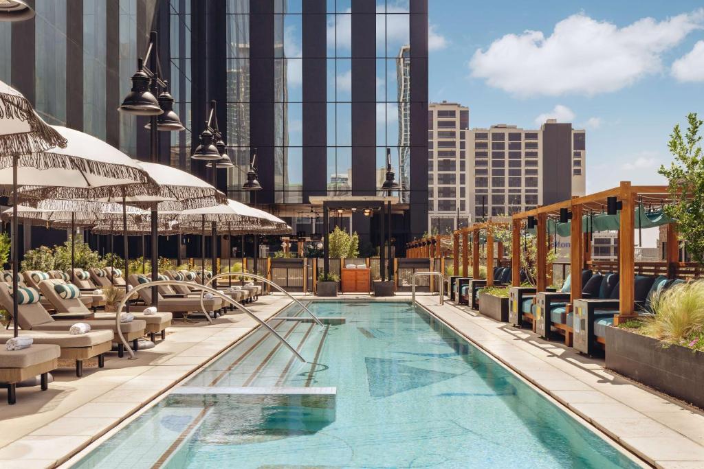 an outdoor pool with chairs and umbrellas on a building at Thompson Austin, by Hyatt in Austin