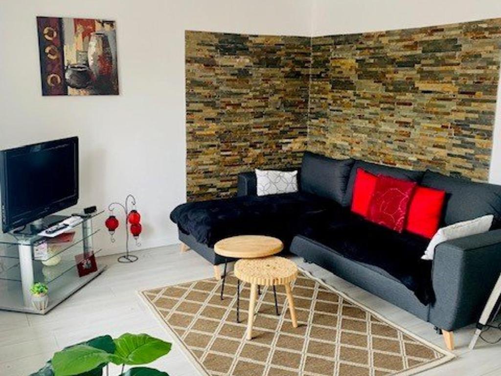 salon z czarną kanapą i czerwonymi poduszkami w obiekcie Charmant F3 climatisé avec balcon ensoleillé, proche centre et Thermes - Amélie-les-Bains - FR-1-703-80 w mieście Amélie-les-Bains-Palalda