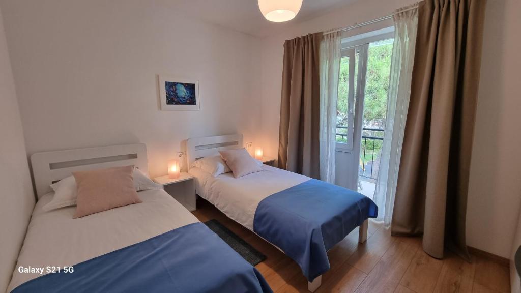 two beds in a room with a window at Apartment Rivarela BLU - newly renovated and top location near sea in Novigrad Istria