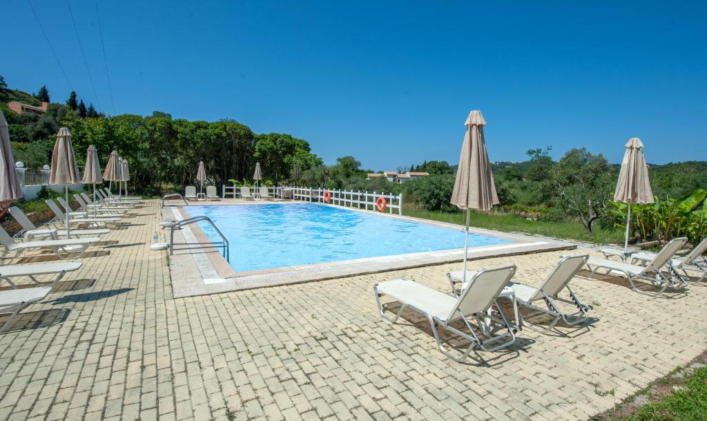 una piscina con sedie a sdraio e ombrelloni di Vassilis Paradise Garden Aparthotel ad Agios Georgios Pagon