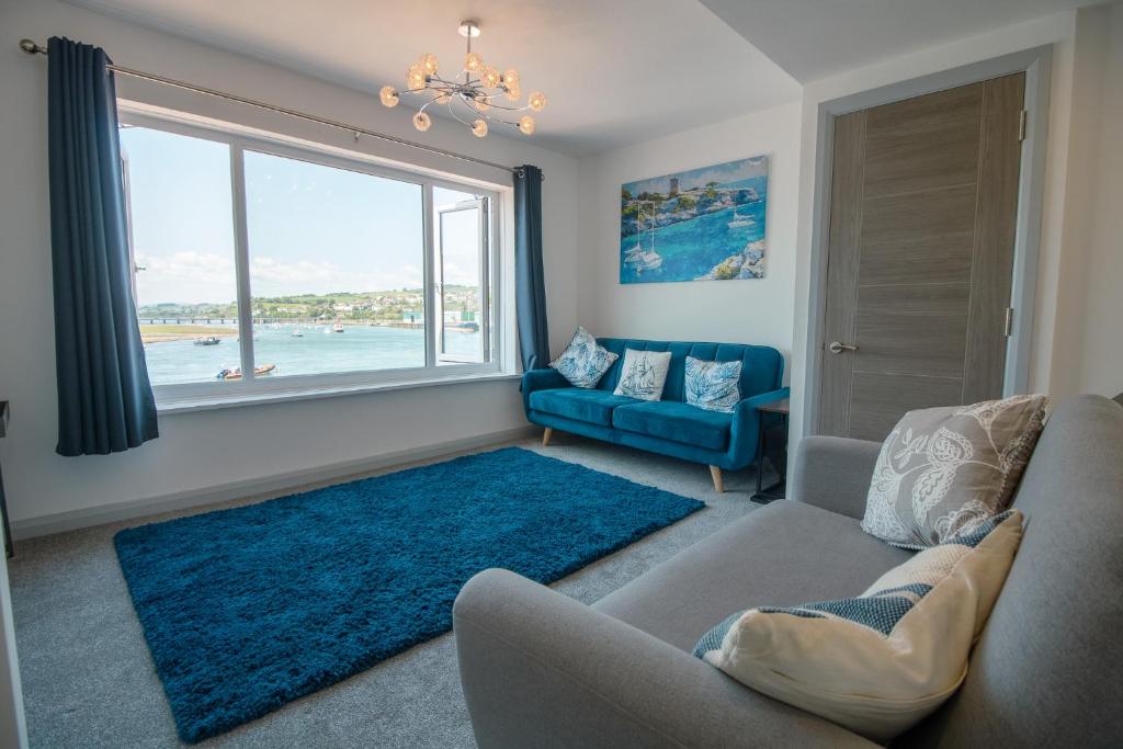 a living room with a blue couch and a large window at Saltwhistle View- Beachside Luxury, Stunning Views in Teignmouth