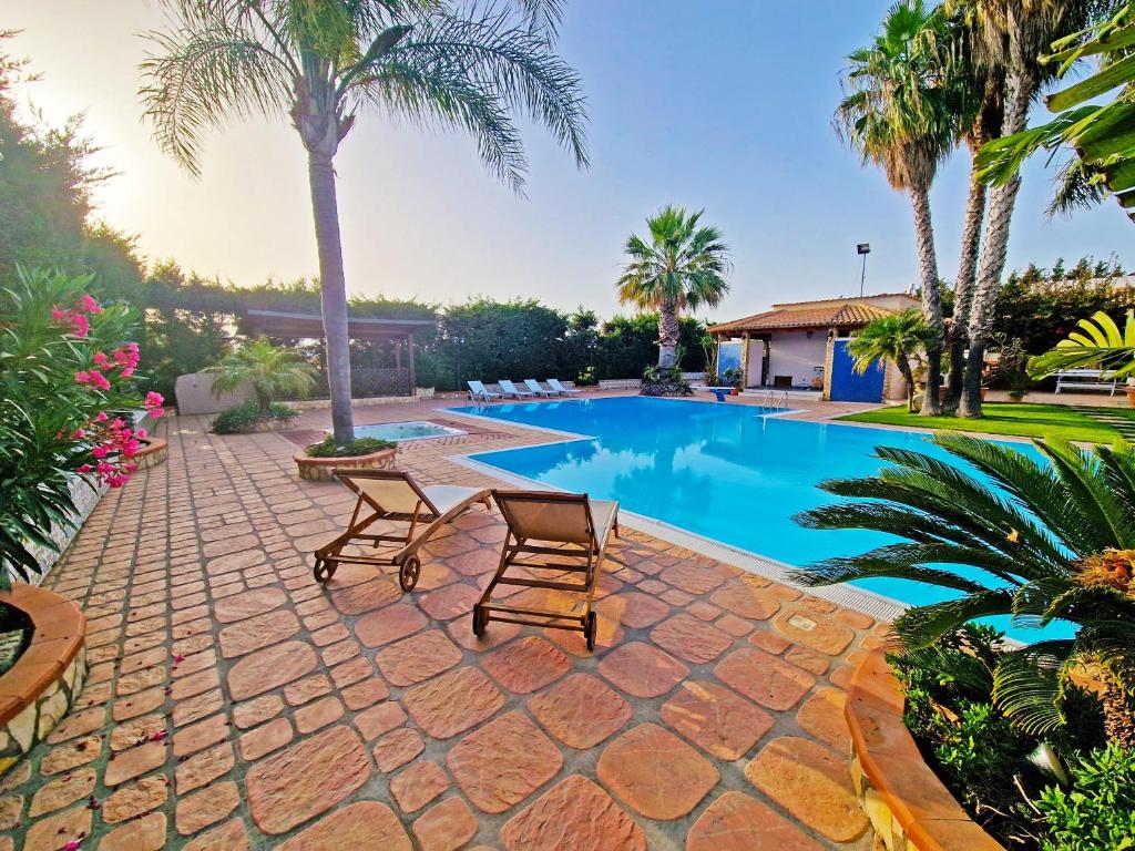 - une piscine avec 2 chaises et des palmiers dans l'établissement Villa Sara, à Borgo Bonsignore