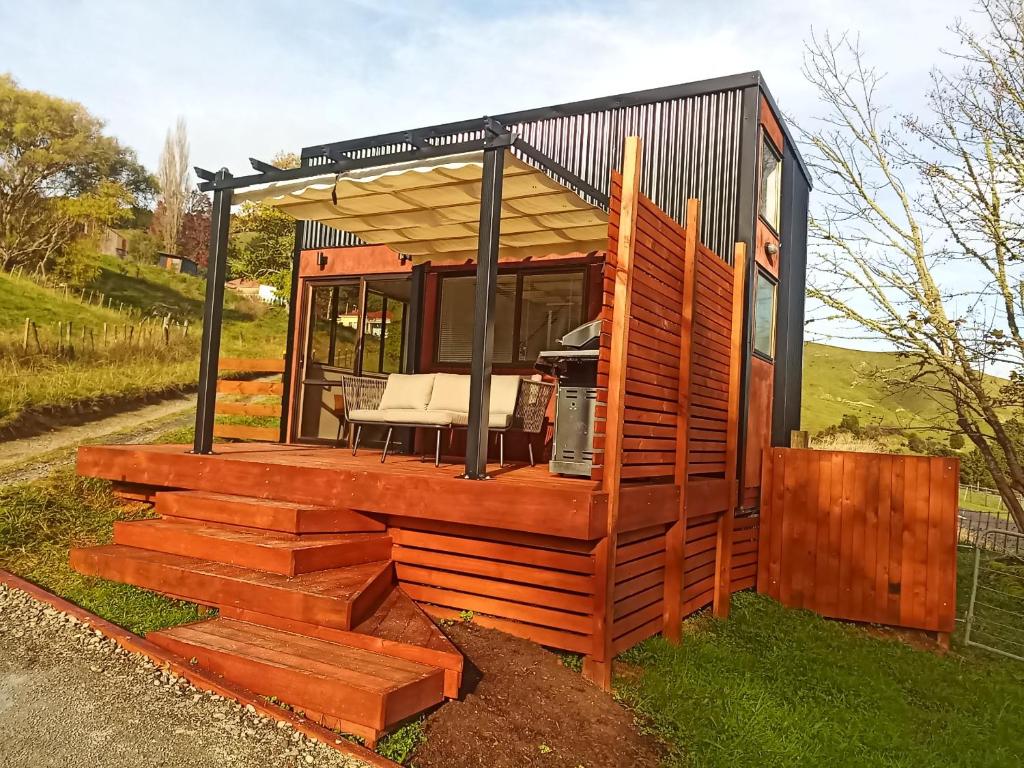a tiny house with a deck on the grass at Tiny home in the hills 