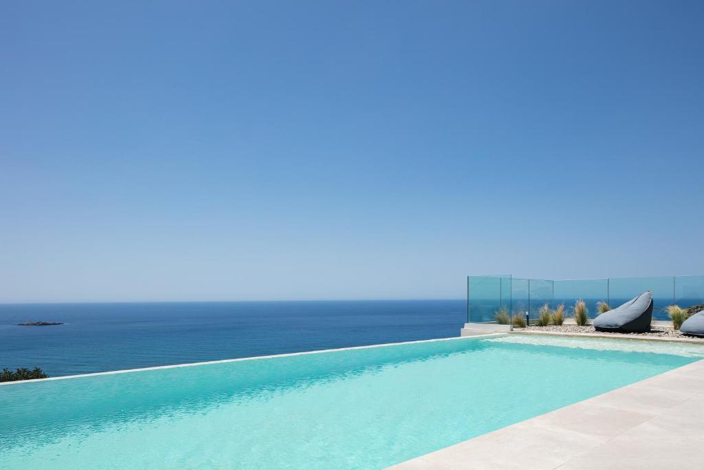 a swimming pool with the ocean in the background at Krystallon Villas in Palaiochora