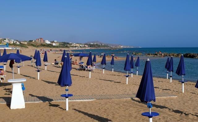 a group of blue umbrellas and chairs on a beach at A Cantunera LittleHouse in Agrigento
