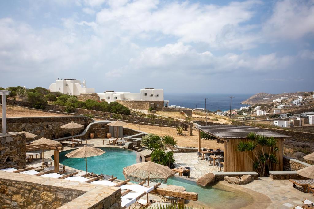 - une piscine avec chaises longues et parasols et l'océan dans l'établissement Nur Mykonian Suites, à Mykonos