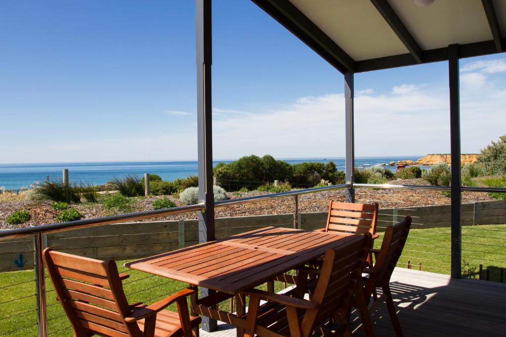 a wooden table and chairs on a balcony with the ocean at Torquay Foreshore Caravan Park in Torquay