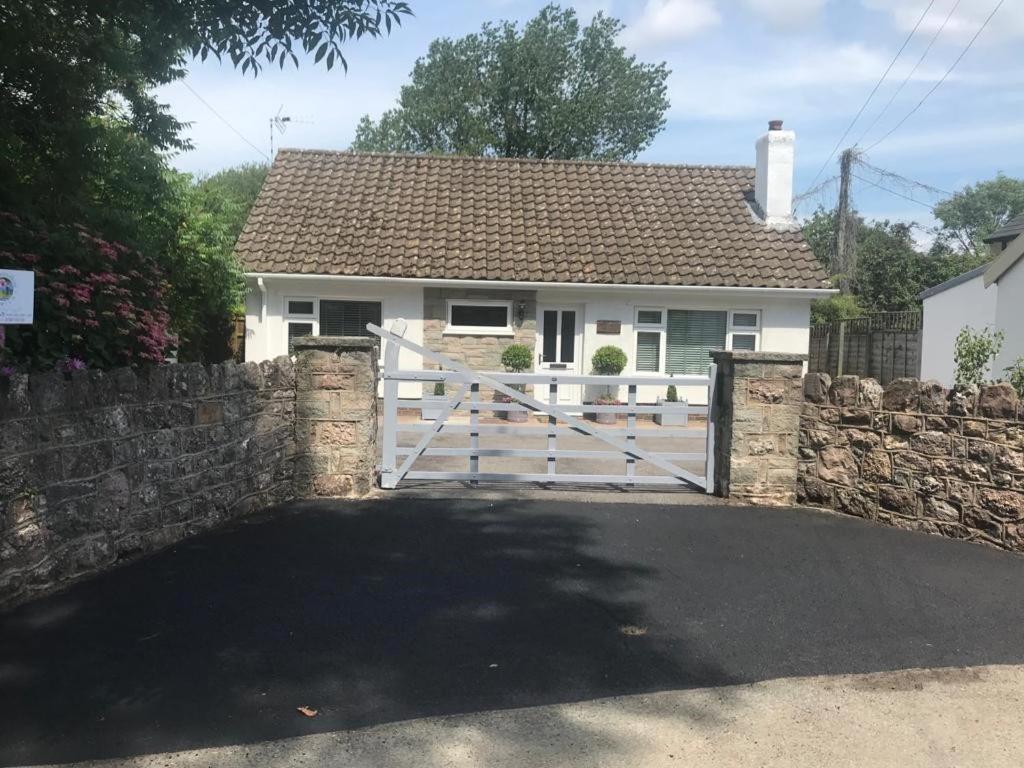 une maison blanche avec un portail et une clôture en pierre dans l'établissement Just Stay Wales - Marshmallow Cottage, Oxwich, à Swansea