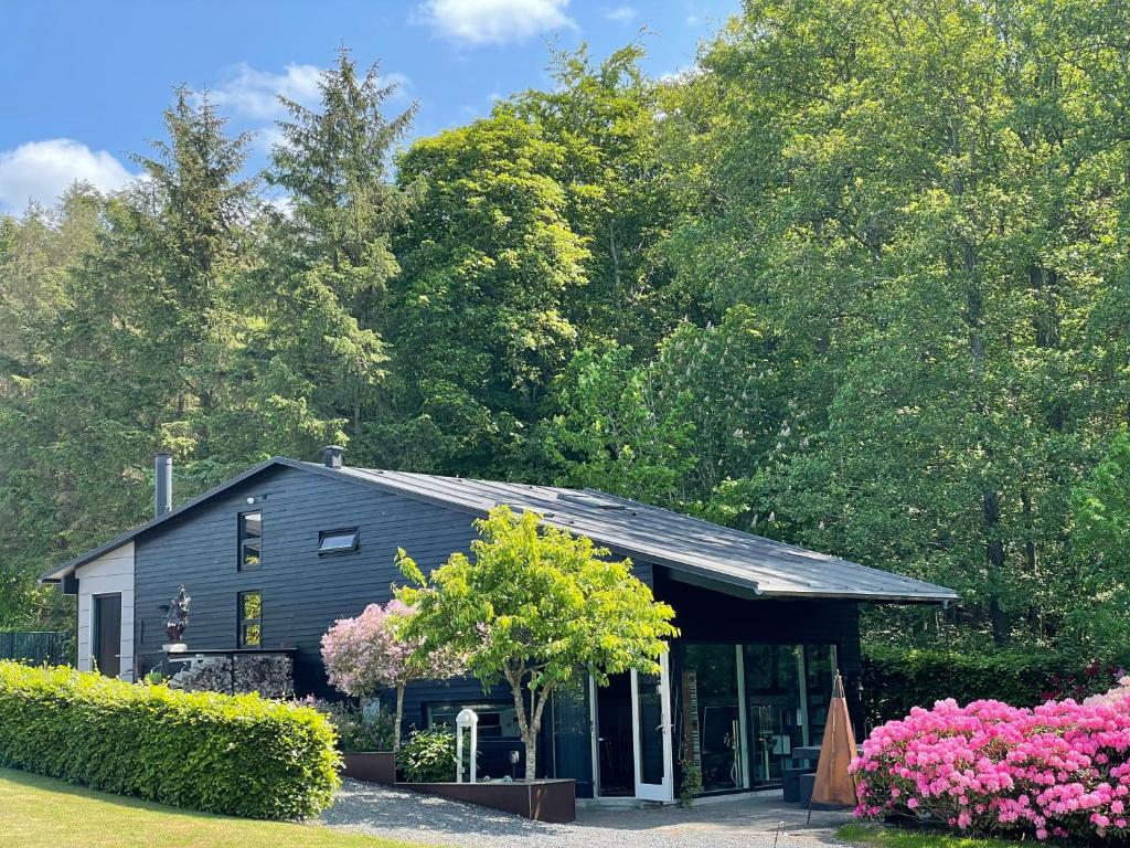 un edificio negro con flores delante en Skovlandshuset, en Hadsten Stationsby