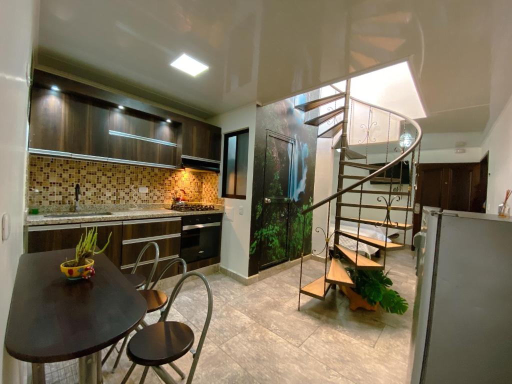 uma cozinha com uma escada em espiral e uma mesa e cadeiras em Los Ríos em Pereira