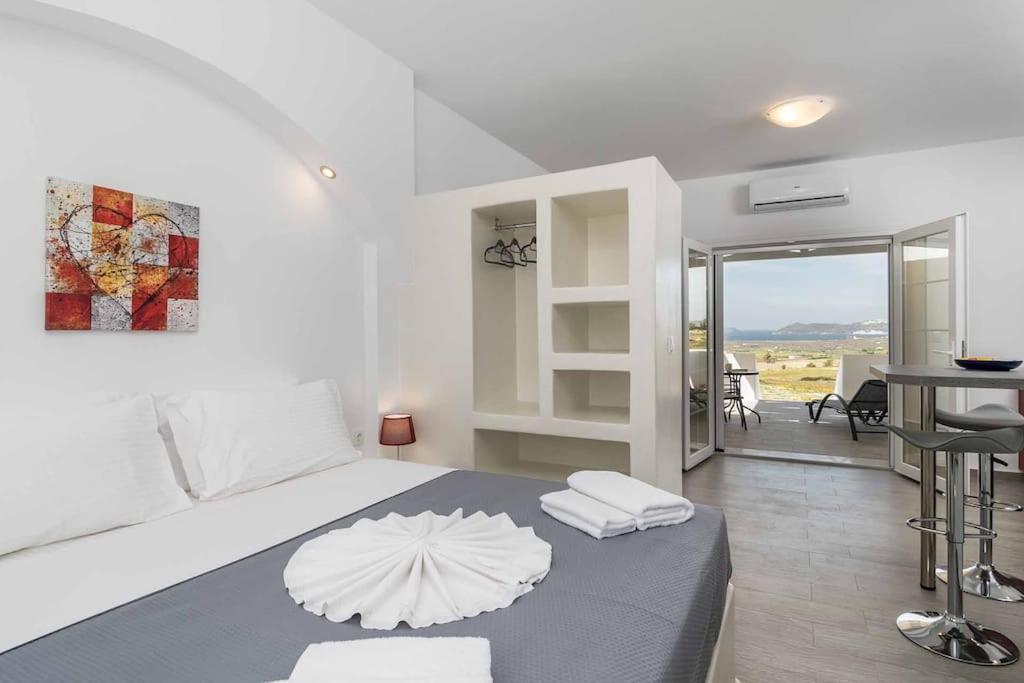 a white bedroom with a large bed with an umbrella on it at Sunset Village 2 in Paleochori