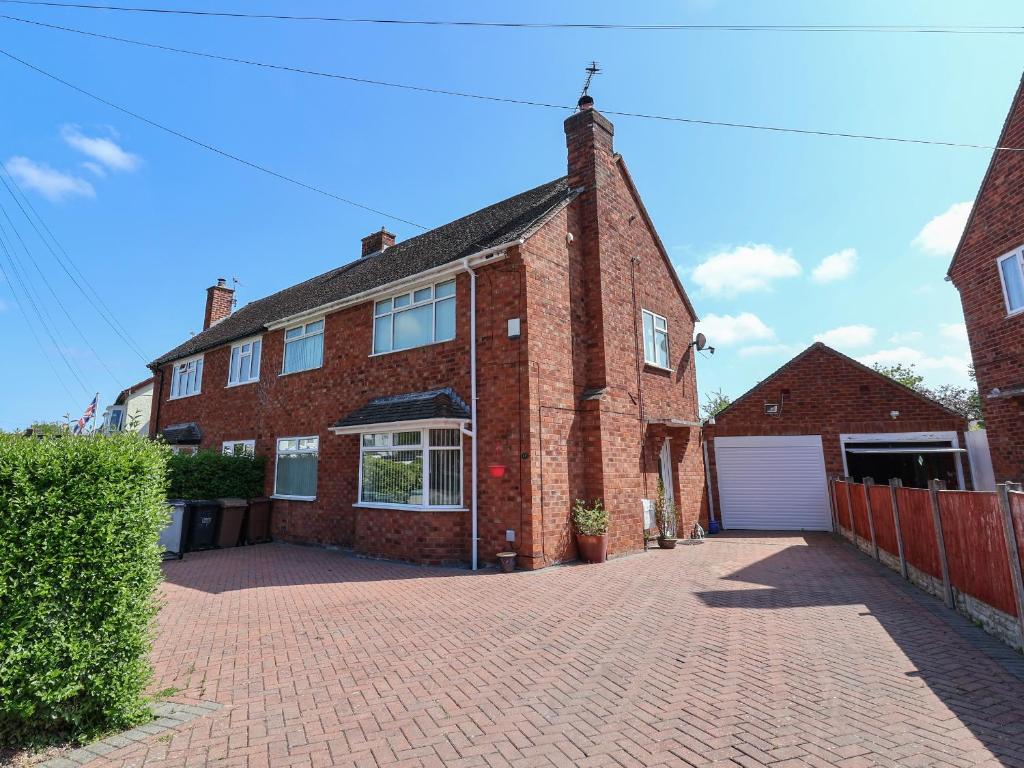 une maison en briques avec un garage dans une allée en briques dans l'établissement 11 Overdale Avenue, à Wirral