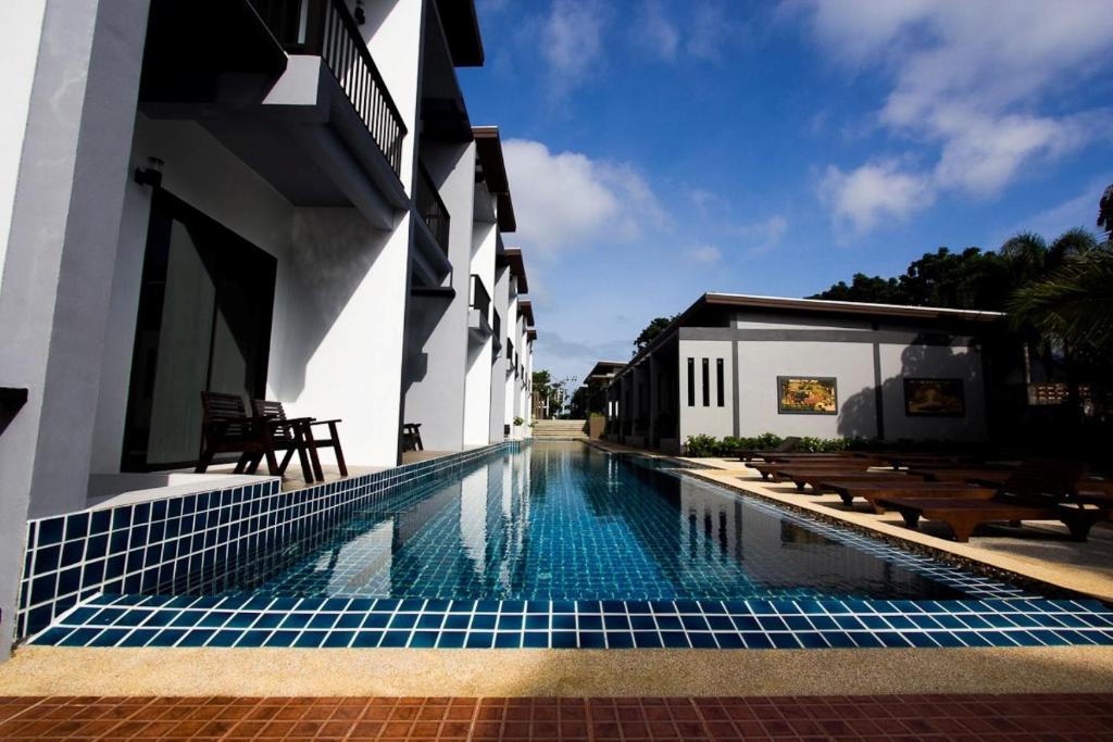 a swimming pool in front of a building at Alphabeto Resort in Nai Harn Beach