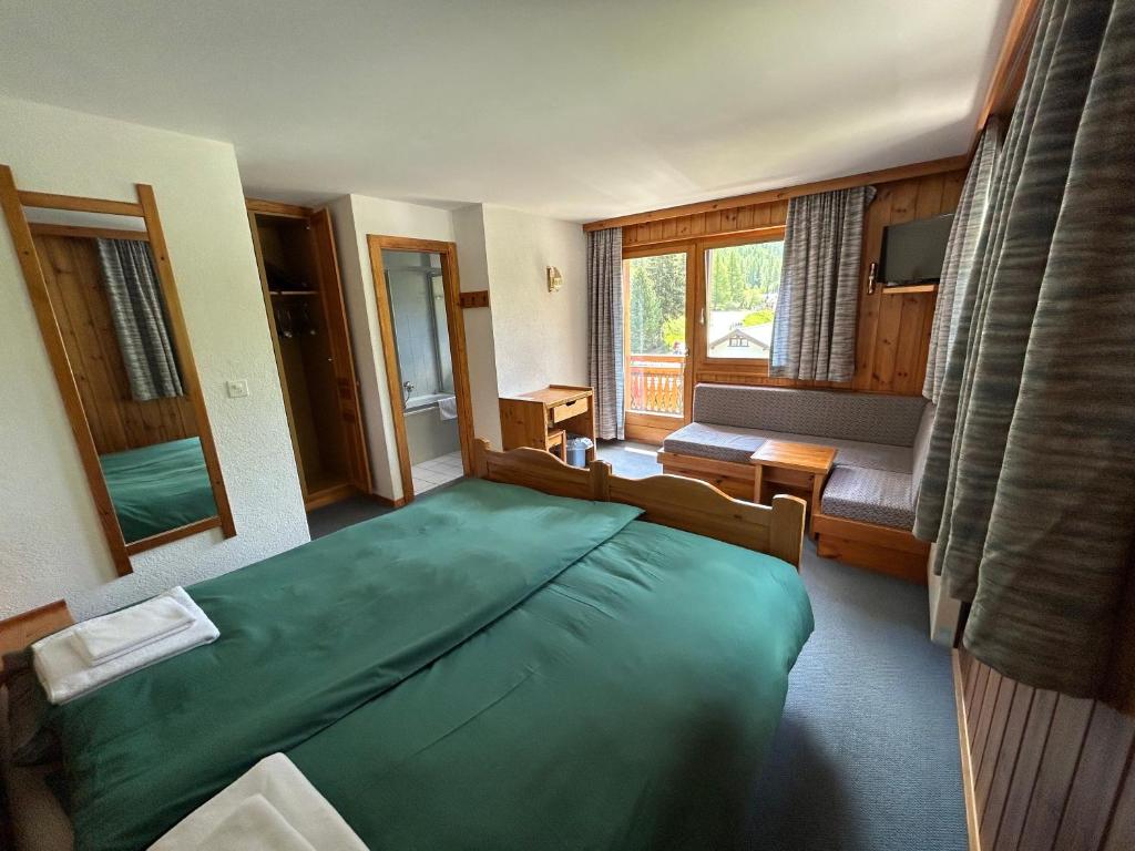 sypialnia z dużym zielonym łóżkiem i oknem w obiekcie Les Bouquetins w mieście Zinal