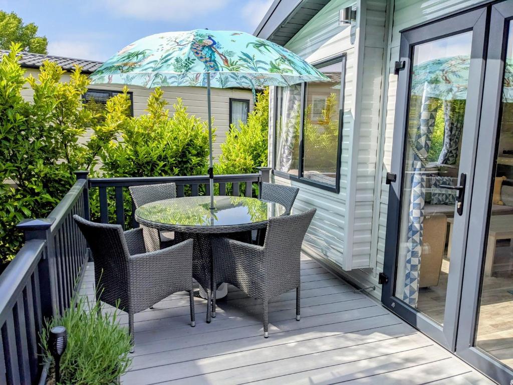 un patio con mesa, sillas y sombrilla en Modern 2 Bedroom Mobile home with parking on St Helens Coastal Resort Isle of Wight en Saint Helens