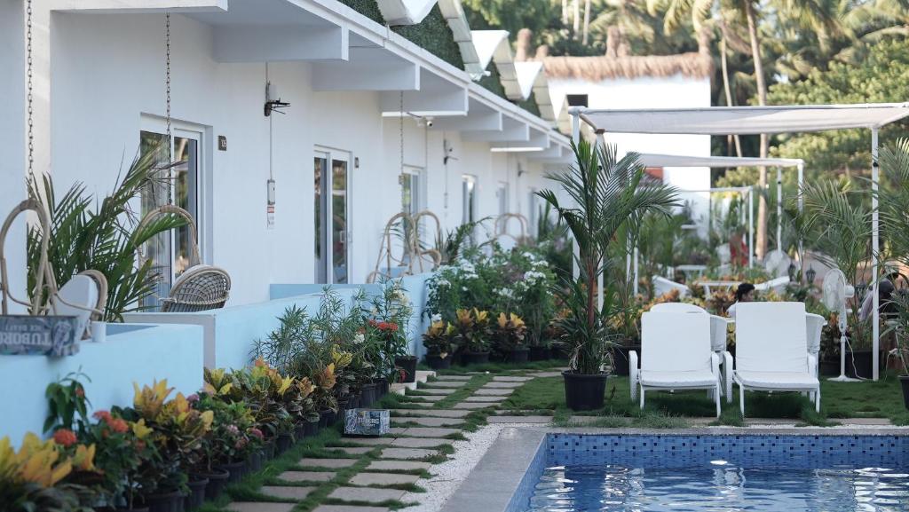 dom z basenem oraz białymi krzesłami i roślinami w obiekcie Whiteflower Resort Morjim w mieście Morjim