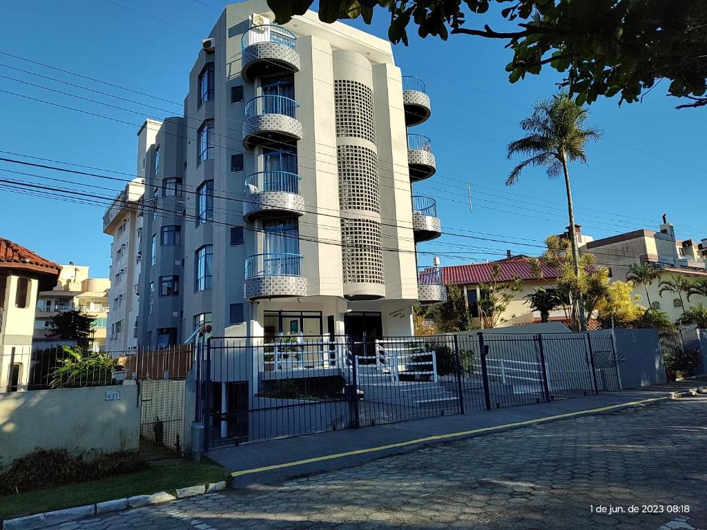 un edificio blanco con una valla delante en Loft encantador a 40 metros do mar., en Florianópolis