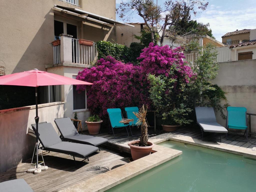 un grupo de sillas y una sombrilla junto a una piscina en Les studios de Marie, en Aviñón