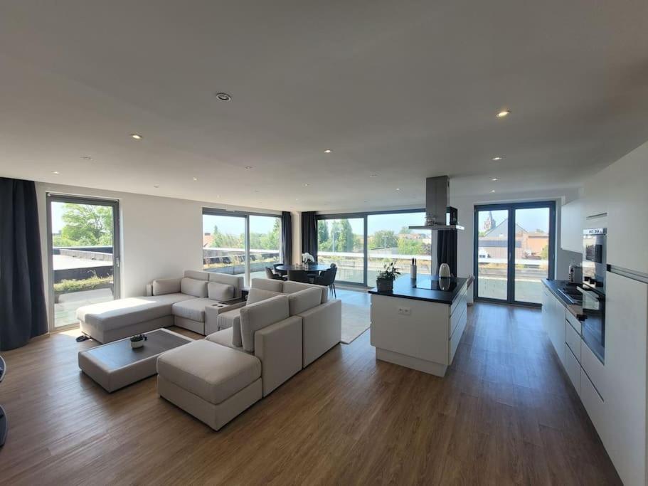 una gran sala de estar con muebles y ventanas blancos. en Luxury Escape, en Blankenberge